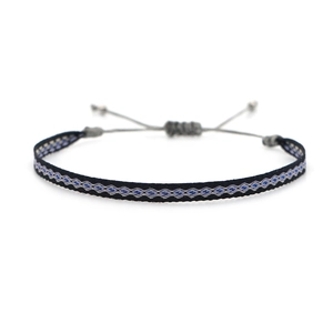 Detail of bohemian hand-woven bracelet featuring blue diamond patterns and grey beads