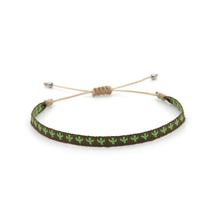 Detailed macro of handwoven ethnic bracelet with green cactus embroidery on brown fabric