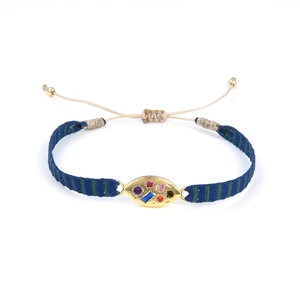 Détail du bracelet tissé avec médaillon ovale doré serti de pierres multicolores