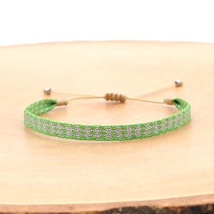 Close-up of handmade woven bohemian bracelet with green and silver geometric patterns