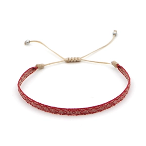 Detail view of Bohemian red hand-woven strap bracelet with white diamond pattern and silver beads