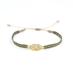 Détail du bracelet tissé olive avec breloque dorée et pierres de zircone incrustées
