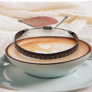 Macro detail of hand-woven geometric bracelet on coffee cup with bohemian styling