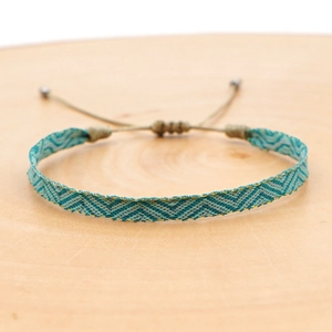 Detail of woven friendship bracelet with blue and green zigzag pattern and gold metallic thread