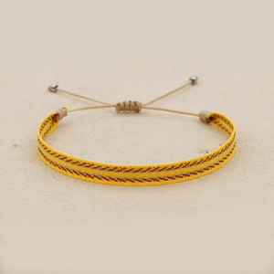Detail of yellow woven friendship bracelet featuring red geometric patterns and sliding knot