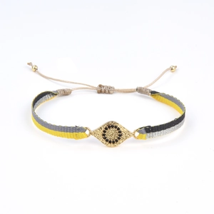 Détail d'un bracelet tressé bohème fait main avec pendentif œil porte-bonheur serti