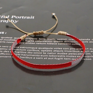 Close-up of bohemian woven bracelet featuring red and silver threads with adjustable cord