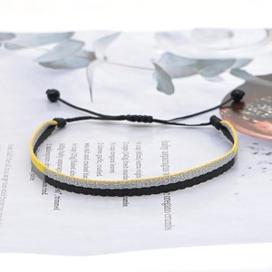 Macro detail of hand-woven striped bracelet with adjustable sliding knot on paper background