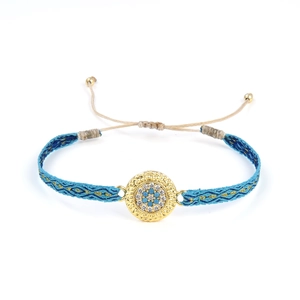 Détails d'un bracelet ethnique fait main avec des fils bleu et or et des cristaux brillants