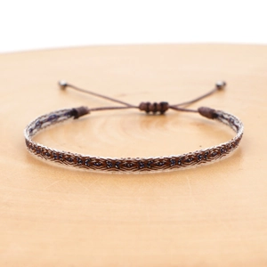 Close-up of bohemian hand-woven ethnic bracelet with adjustable brown cord and beads