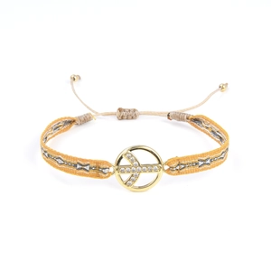 Détail d'un bracelet ethnique tressé avec pendentif croix dorée et cordon réglable