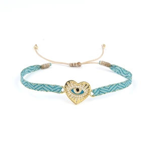 Détail du bracelet cœur mauvais œil tissé main avec finition dorée et design émaillé bleu