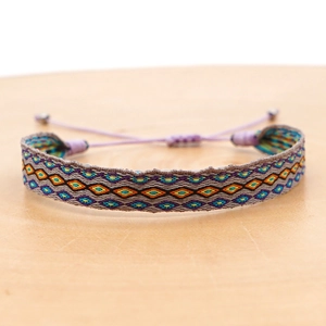 Macro shot of colorful bohemian woven bracelet with geometric patterns on wood