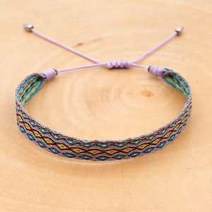 Macro detail of Bohemian embroidered woven bracelet with geometric patterns on wood