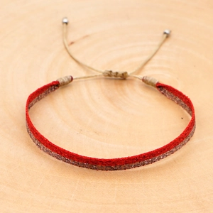 Macro shot of handmade red and gold woven bohemian bracelet on a natural wood surface