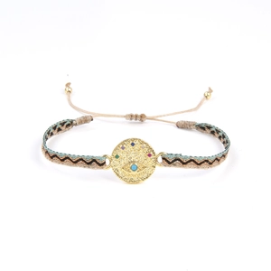 Vue détaillée du bracelet bohème tissé avec un médaillon œil porte-bonheur doré et pierres colorées