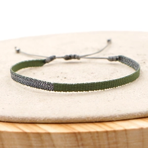 Detail of army green and silver woven bohemian bracelet with adjustable cord closure