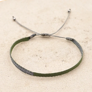 Macro detail of hand-woven dark green and silver cord bracelet with adjustable beads