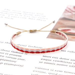 Macro detail of Bohemian woven friendship bracelet with red wave patterns and silver beads