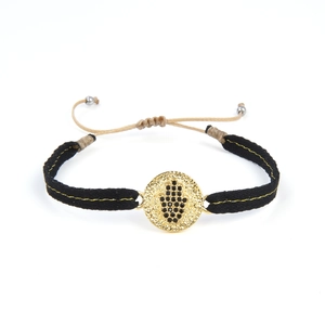 Détail macro du bracelet Hamsa tressé à la main avec breloque dorée et perles noires