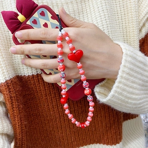 Detail of handmade beaded phone strap with red acrylic heart and floral pattern beads