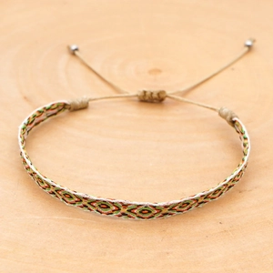 Detail of bohemian woven bracelet with geometric diamond patterns on wooden surface