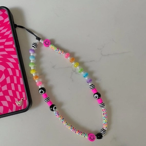 Detailed close-up of rainbow bead phone lanyard with evil eye and smiley charms