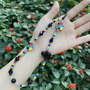 Colorful beaded phone charm with black heart and peace symbols held by hand