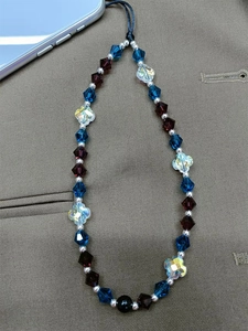 Handmade beaded phone strap with blue and purple clover crystal beads on grey smartphone