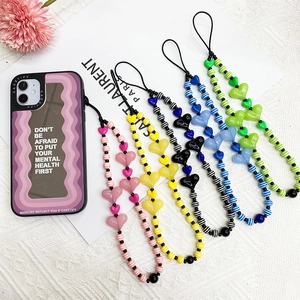 Colorful acrylic heart bead phone straps and patterned cases on a textured background