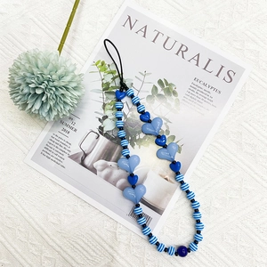 Close-up of blue heart-shaped acrylic beads and striped round beads on a phone lanyard