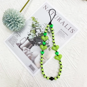 Detail of green acrylic heart beads and striped round charms on a stylish phone lanyard