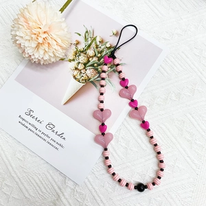 Detail of pink acrylic heart beads and striped round charms on a handmade phone wrist strap