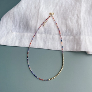 Minimalistische 2mm gekleurde zirkoon kralenketting met gouden sluiting op witte stof