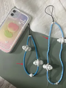 Detail view of handmade phone strap with blue glass beads and white cloud charms