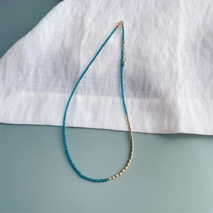 Detail van 2mm zirkoon ketting met blauwe kralen, gouden accenten en een karabijnsluiting