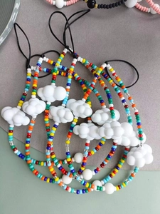 Macro detail of colorful beaded phone straps with white resin cloud charms in various colors