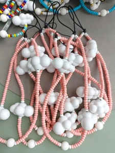 Detail of handmade beaded phone straps featuring pink beads and white cloud charms