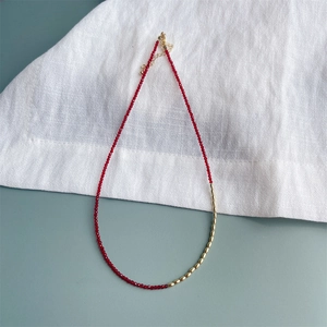 Detail van een 2mm rode zirkoon halsketting met gouden metalen accenten en karabijnslot