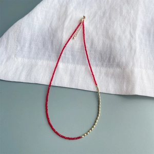 Detailopname van 2mm rode zirkoon kralen en gouden ovale schakels op de ketting