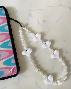 Chic white acrylic heart beaded phone strap on floral case against marble surface