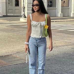White bustier top and crossover waist jeans set with a green shoulder bag