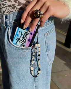 Handmade beaded phone strap with white baroque pearls and black charms on denim pocket