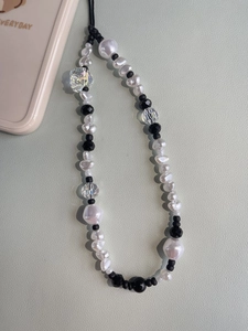 Beaded phone charm with white baroque pearls and colorful skull bead on leather background