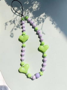 Beaded phone strap with green hearts and purple striped beads on a light background