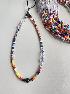Handmade bohemian beaded phone strap with colorful crystal beads on gray background