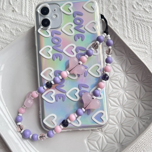 Détail d'une dragonne de téléphone perlée rose et violette avec breloque cœur sur coque