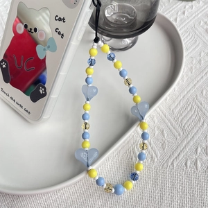 Détail du bijou de téléphone perles cœur bleu et jaune sur coque de téléphone chat blanc