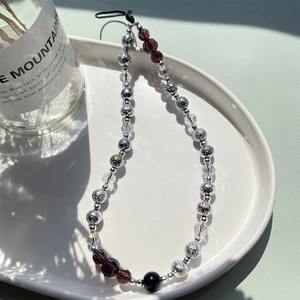Chic beaded phone wrist strap with iridescent silver and purple beads on ceramic tray