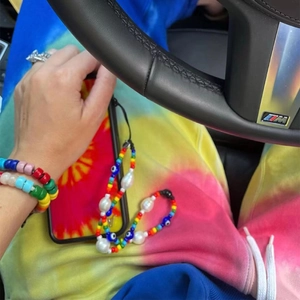 Close-up of rainbow beaded phone strap with pearls and evil eye charm in hand